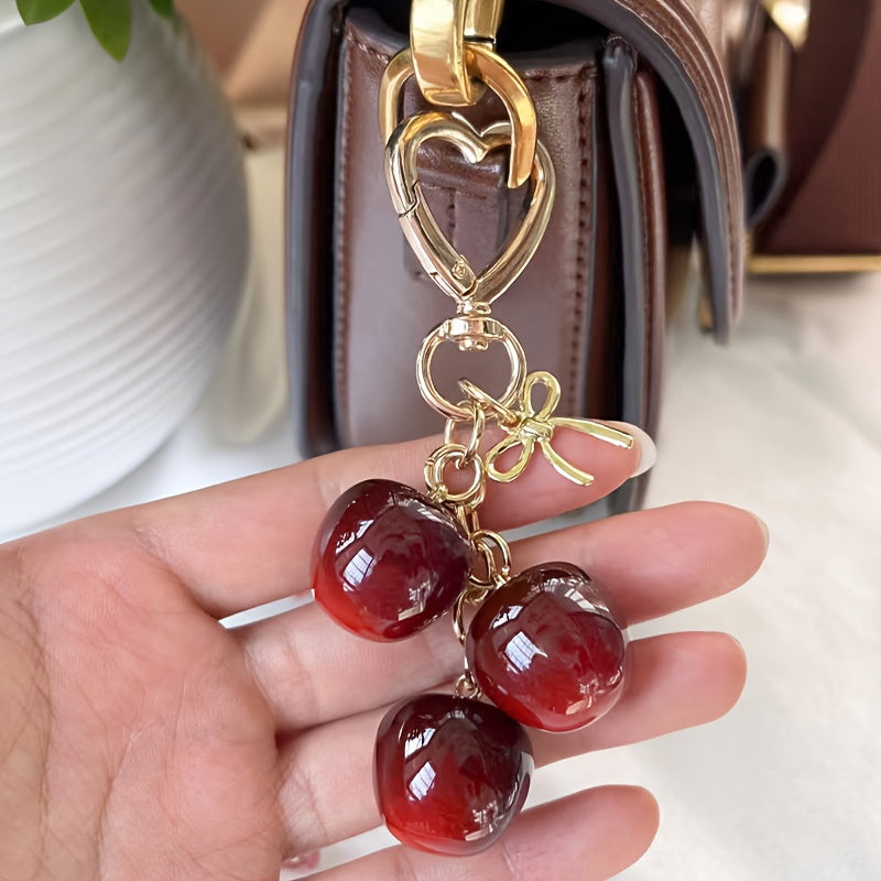 Portachiavi a forma di ciliegia con fiocco e ciondolo a forma di cuore - Resina rossa, finiture dorate - Ideale per borse da donna, portafogli, accessori per San Valentino, ciondolo per borsa a forma di ciliegia
