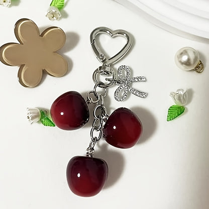 Portachiavi a forma di ciliegia con fiocco e ciondolo a forma di cuore - Resina rossa, finiture dorate - Ideale per borse da donna, portafogli, accessori per San Valentino, ciondolo per borsa a forma di ciliegia